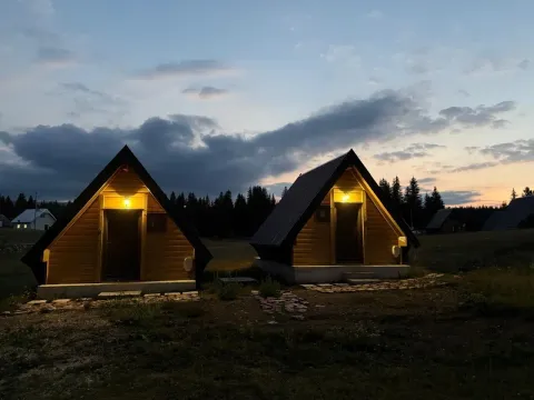 Eksterijer drvenih bungalova u sumrak sa osvijetljenim ulazima. - image 7