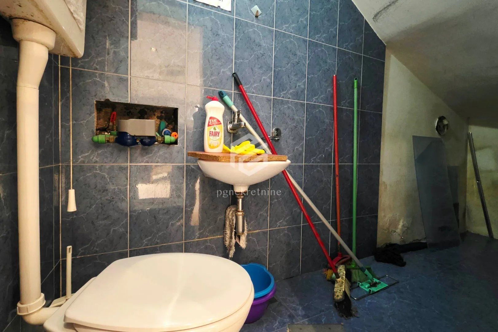 Small bathroom with tiles, washbasin and toilet.