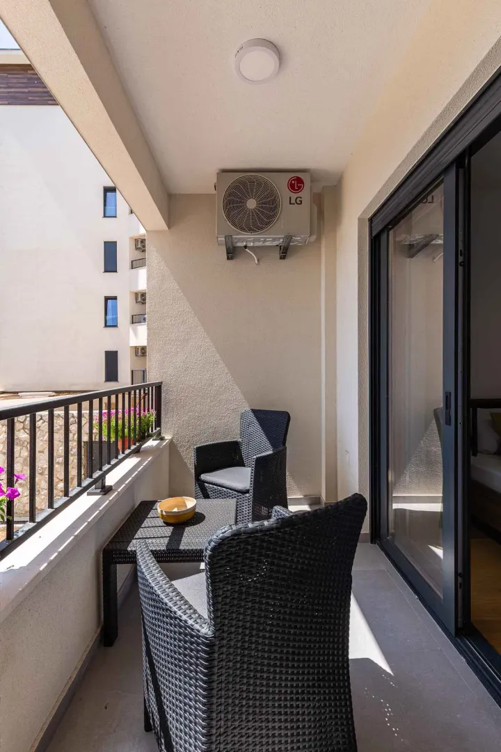 Namješten balkon sa garniturom za sjedenje i klima uređajem.