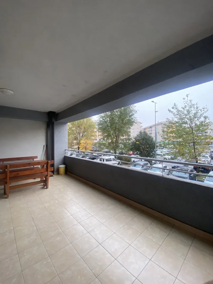 A spacious tiled terrace with a wooden bench and a view of the surroundings.