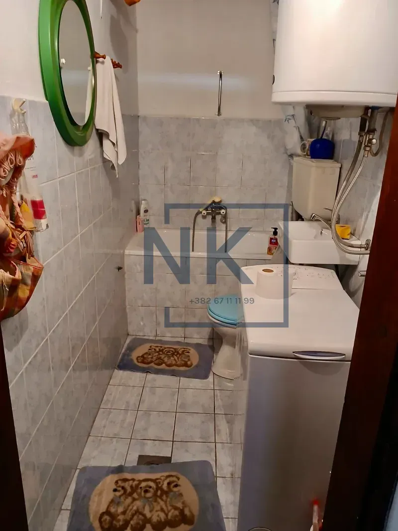 Manje kupatilo sa kadom, wc šoljom, umivaonikom i veš mašinom.