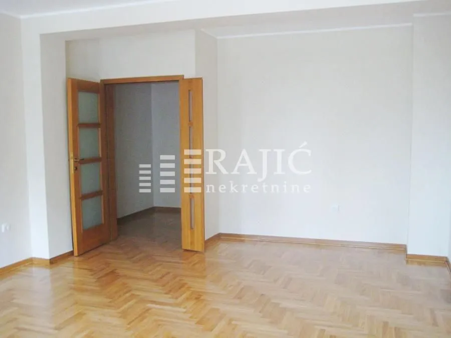 Empty room with parquet flooring and wooden doors.