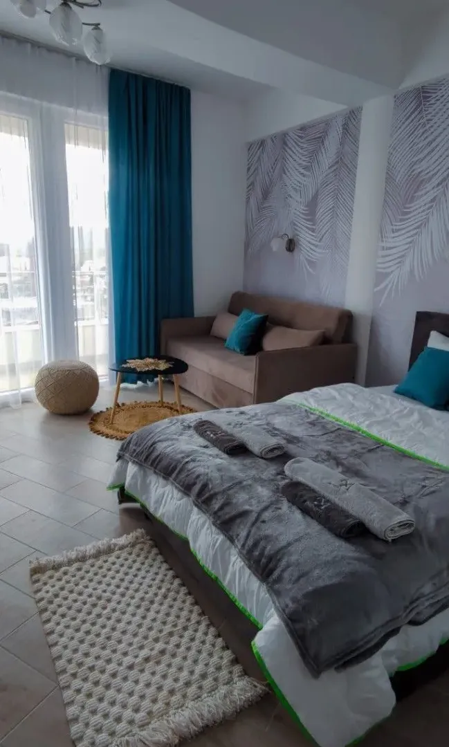 Furnished bedroom with a double bed, sofa, and balcony access.