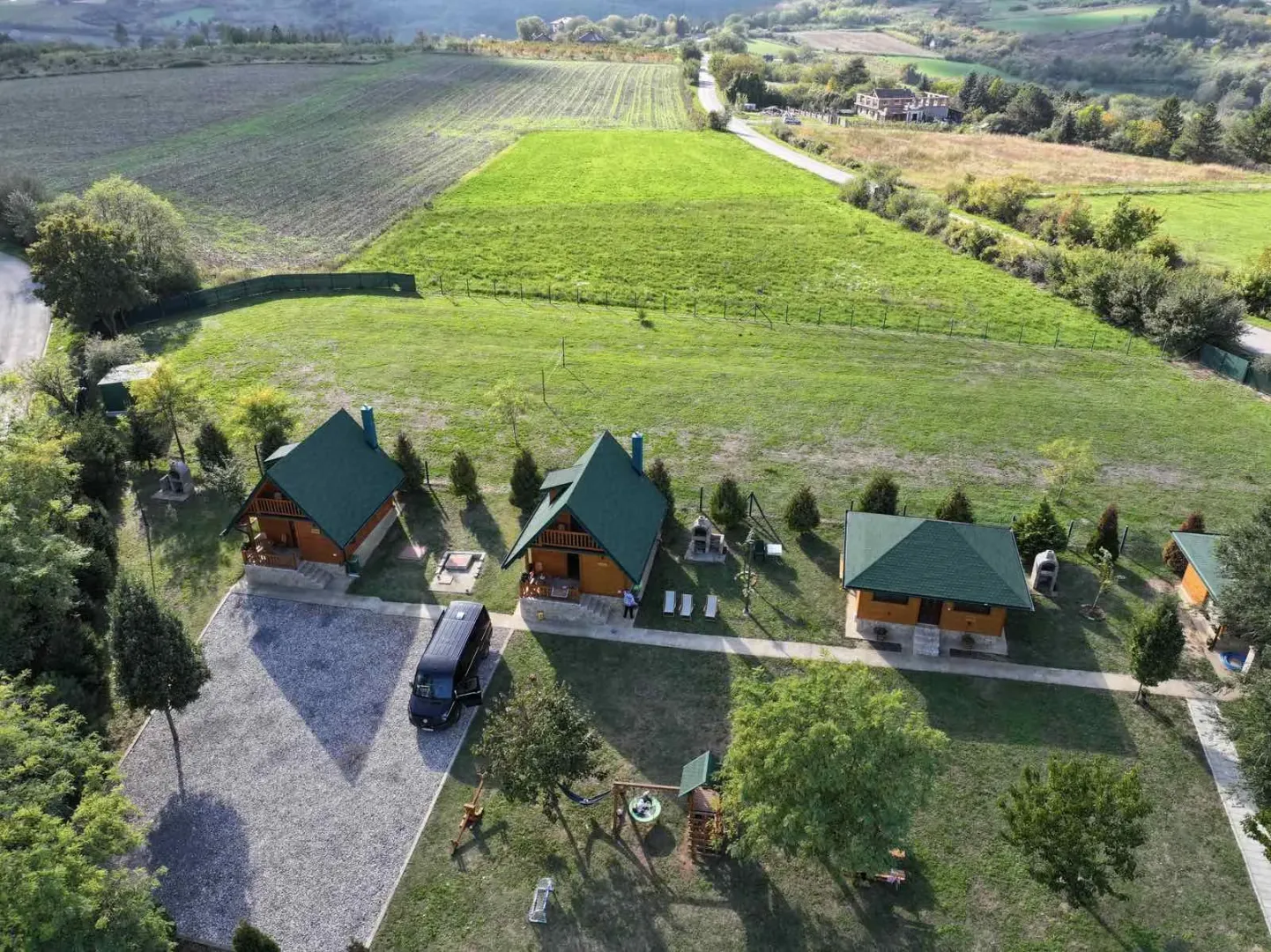 Pogled iz vazduha na drvene kućice u dvorištu sa zelenom površinom i okolinom.