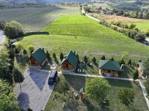 Pogled iz vazduha na drvene kućice u dvorištu sa zelenom površinom i okolinom. - image 17