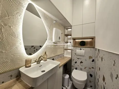 Modern bathroom with a sink, toilet, and illuminated mirror. - image 3