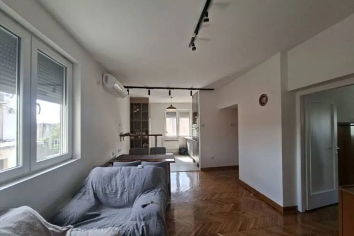 Living room with sofa and a view towards the dining area and kitchen.