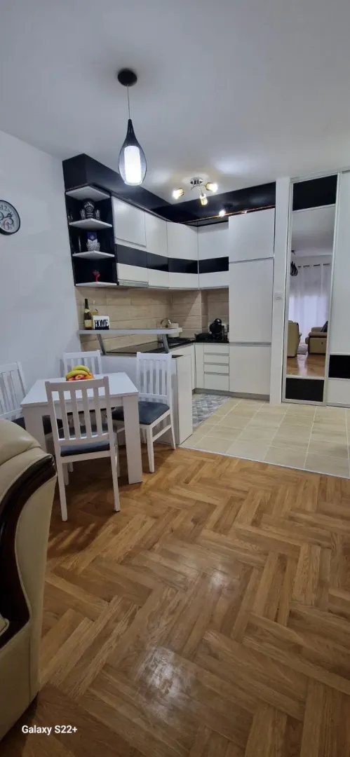 Modern kitchen with a dining area and parquet flooring.