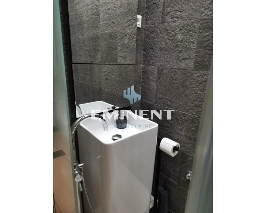 View of the sink and dark wall tiles in the bathroom.