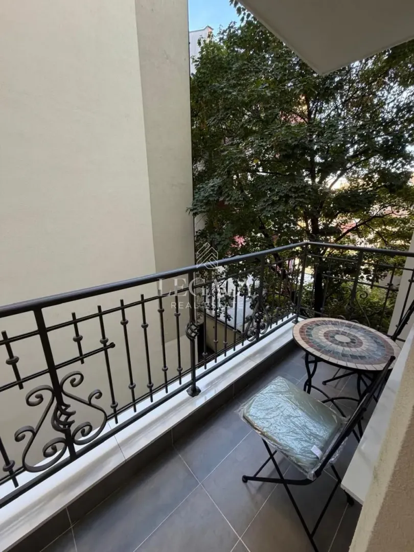 Small balcony with a metal railing and a small table with a chair.