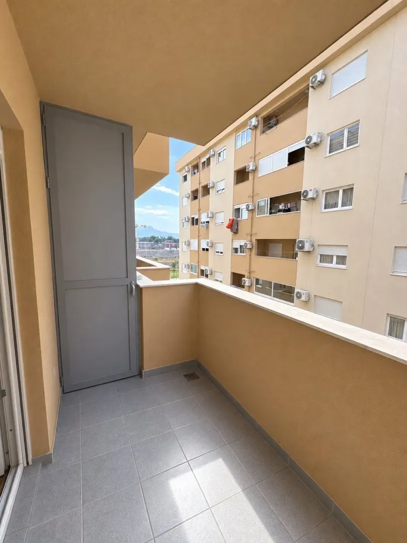 Manji popločani balkon sa vratima i pogledom na susjednu zgradu.