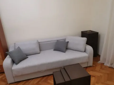 A simple living room featuring a grey sofa and wooden parquet flooring. - image 2