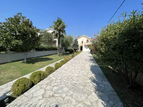 A stone path leads to a house surrounded by greenery and trees. - image 2