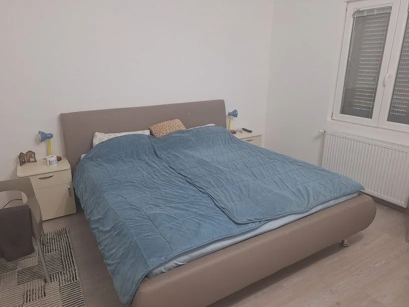 Nameštena spavaća soba sa bračnim krevetom i noćnim stočićima.