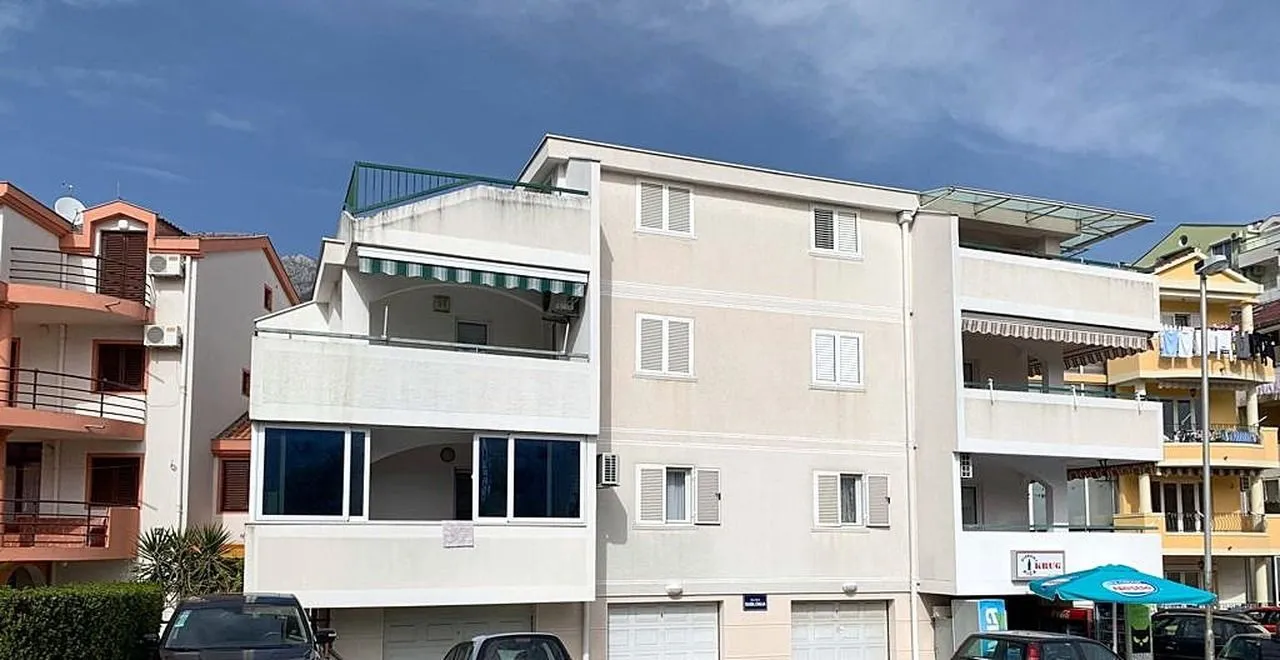 Exterior view of the apartment building with terraces and parked cars in front.