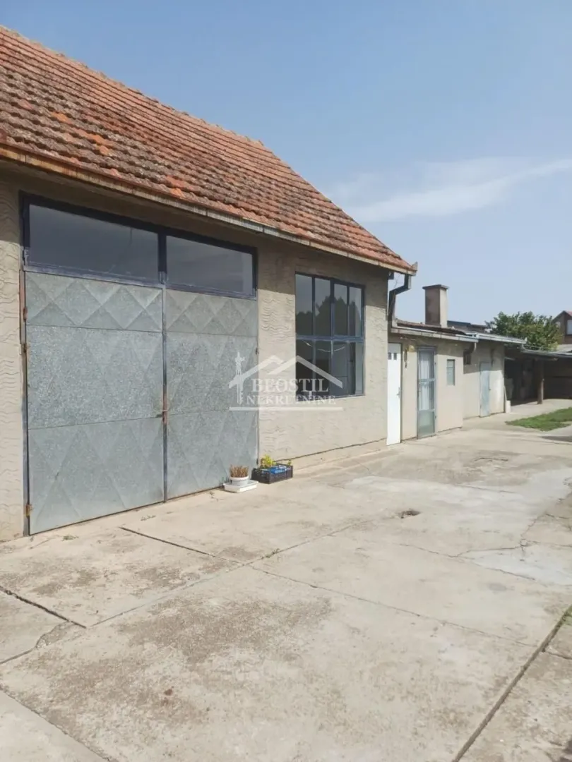 Pogled na eksterijer prizemnog objekta sa dvorištem i betonskom podlogom.