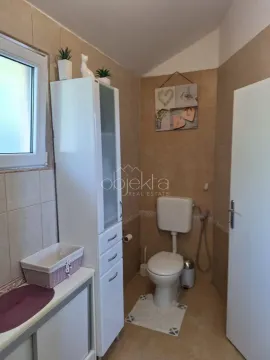 Kupatilo opremljeno toaletom, bijelim ormarićem i prozorom. - image 7