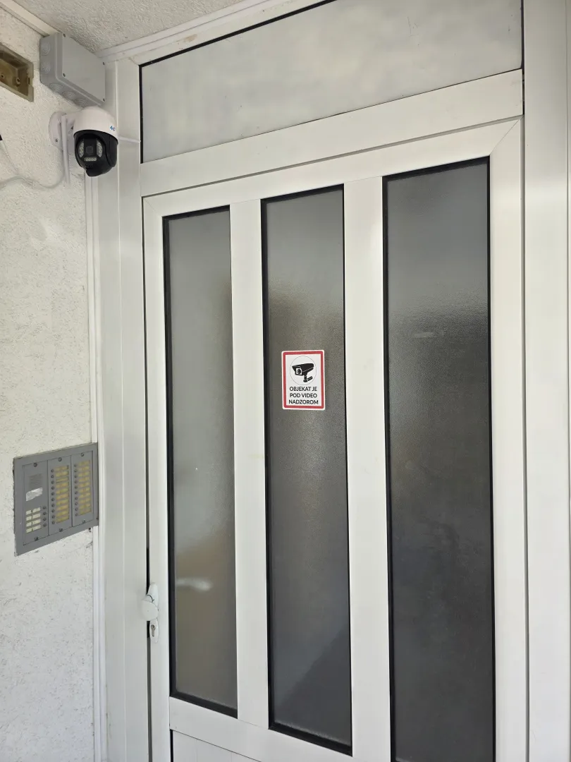 Building entrance door with an intercom and a security camera.
