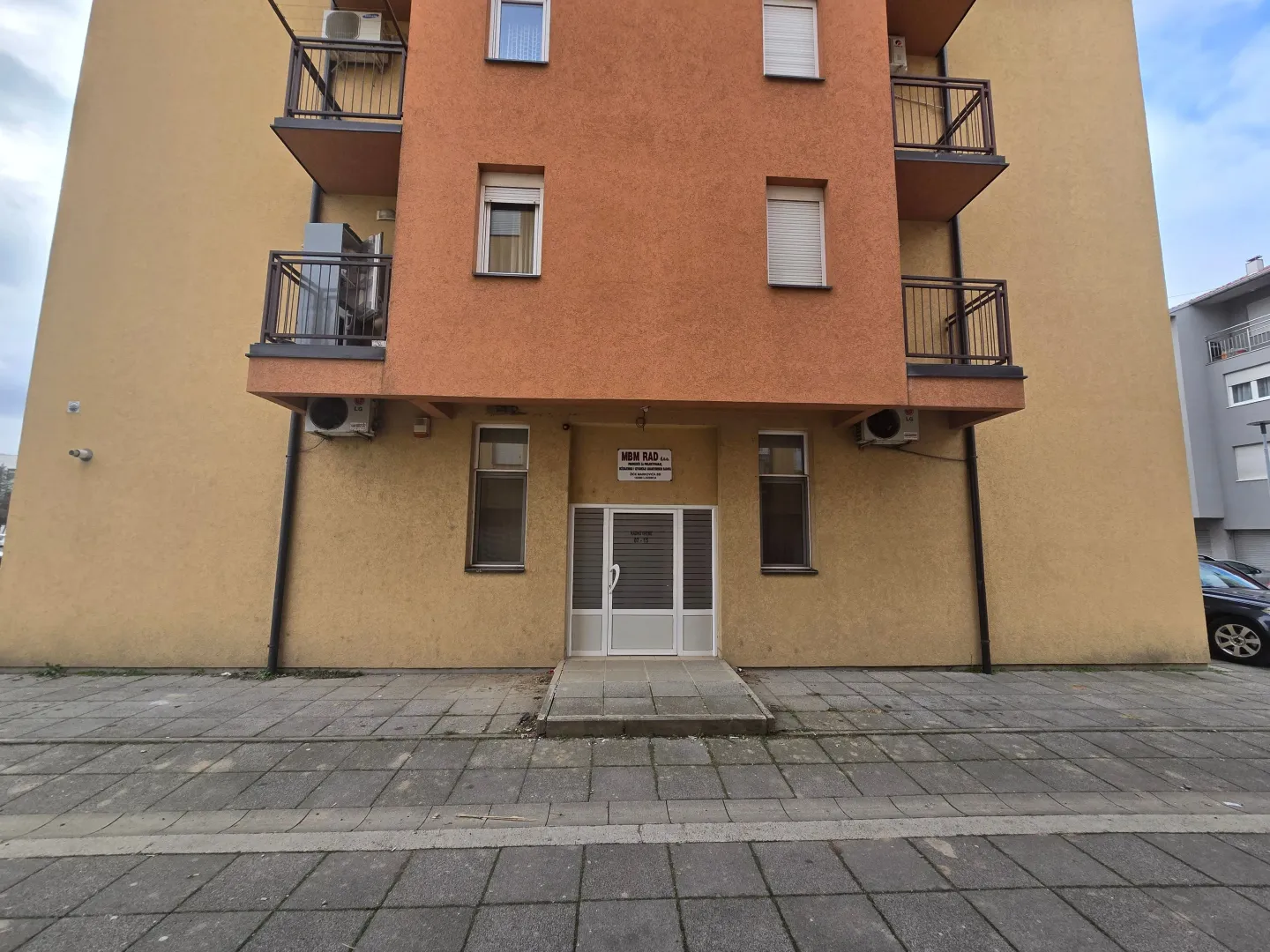 Fasada i ulaz u stambenu zgradu sa balkonima.
