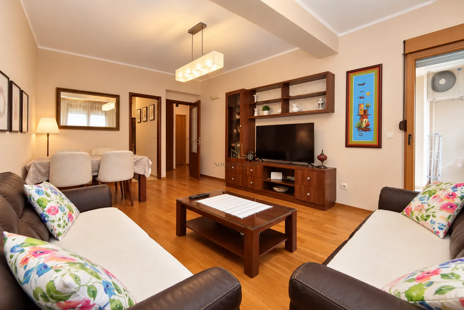 Spacious living room with a sofa set, TV, and a dining area in the background.