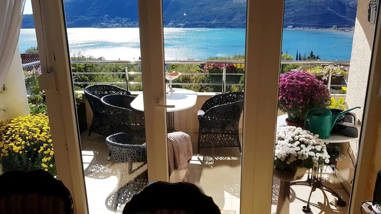 Namješten balkon sa pogledom na more kroz staklena balkonska vrata.