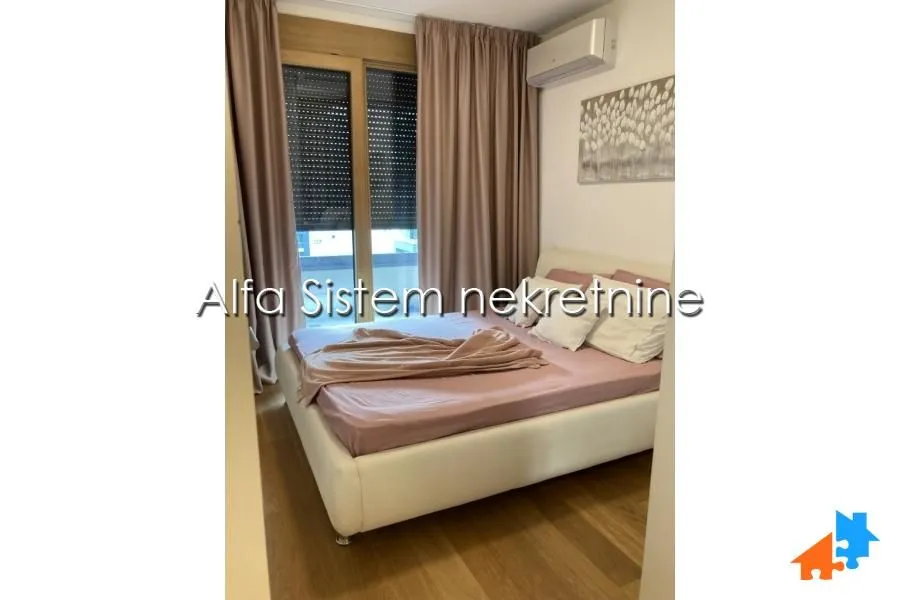 Furnished bedroom with a double bed and a window with curtains.