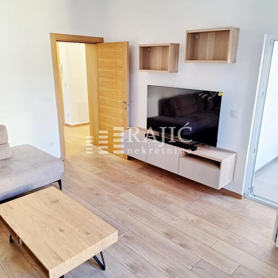 Living room with a sofa, TV console unit, and wooden flooring.