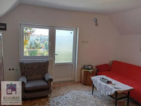 Dnevna soba sa crvenim kaučem, foteljom i prozorom sa pogledom na okolinu. - image 6