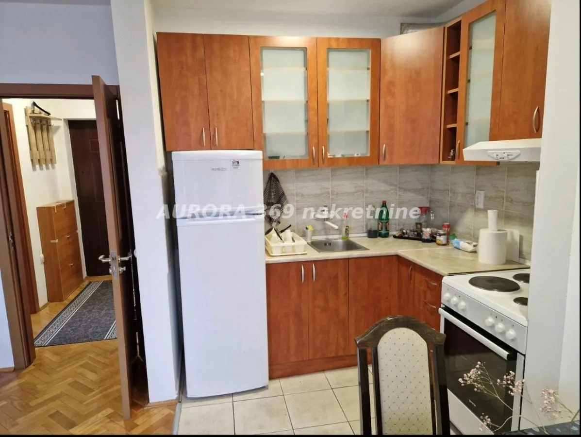 Small kitchen with wooden cabinets, refrigerator, and stove.