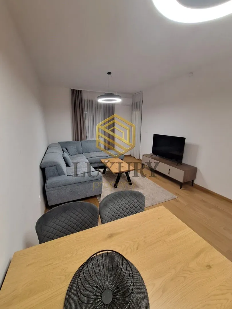 Living room with a corner sofa, TV, and dining table in the foreground.
