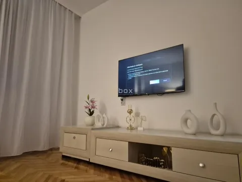 Dnevna soba sa televizorom na zidu i komodom ispod. - image 5
