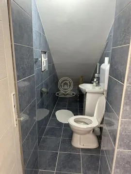 Manje kupatilo obloženo tamnim pločicama sa kosim plafonom i sanitarijama. - image 4