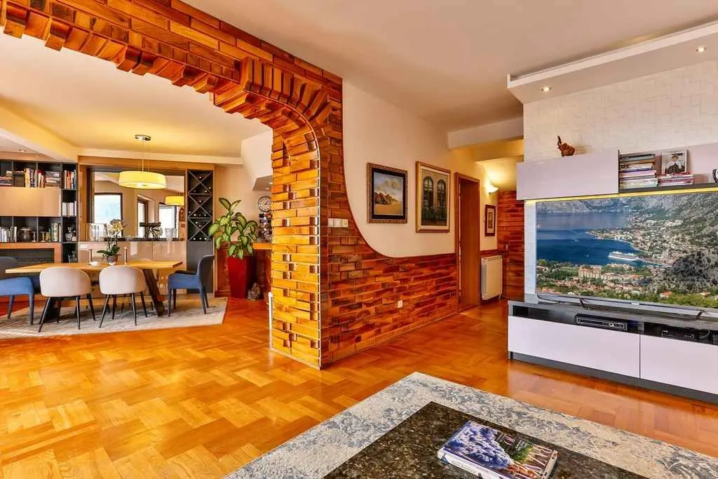 Spacious living room featuring a decorative wooden arch and a dining area in the background.