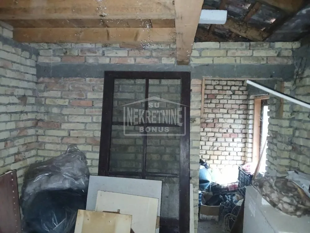 Pogled na nenamještenu prostoriju u izgradnji sa ciglenim zidovima i drvenim gredama.