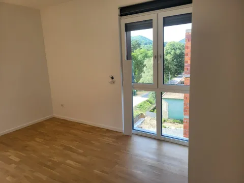 Prazna soba sa parketom i prozorom koji gleda na zelenilo. - image 4