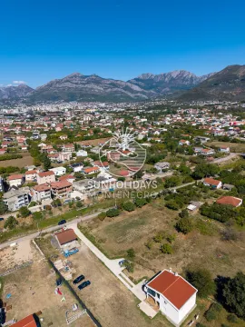 Pogled iz vazduha na grad i okolno naselje sa planinama u pozadini. - image 6