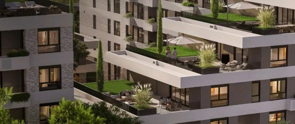 Spoljašnji izgled moderne stambene zgrade sa terasama i uređenim zelenim površinama.