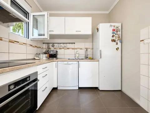 Bijela kuhinja sa ugradnim elementima i bijelim frižiderom. - image 6