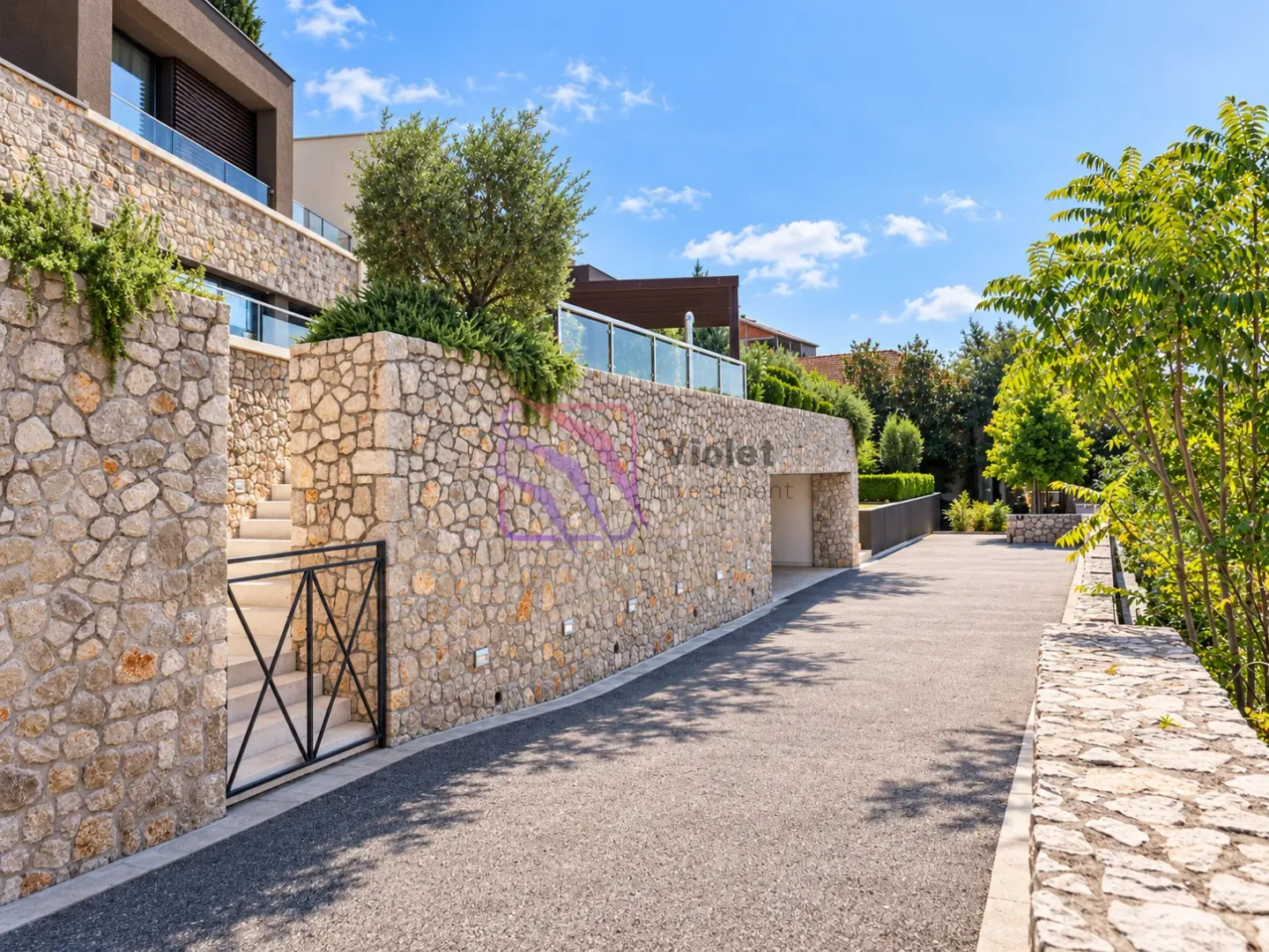 View of the driveway and stone facade of the house with a landscaped yard.