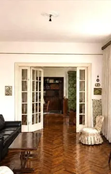 Dnevna soba sa drvenim parketom i dvokrilnim staklenim vratima koja vode u drugu prostoriju. - image 3