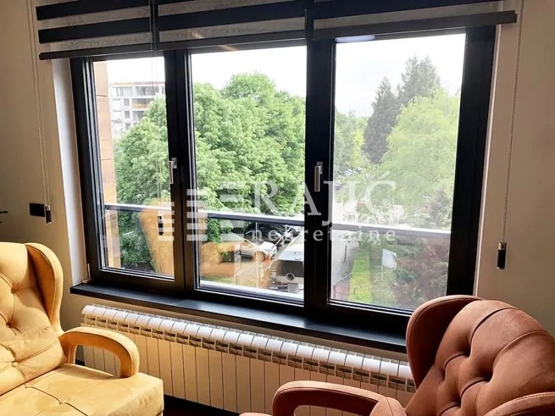 Living room with armchairs by the window and a view of greenery.