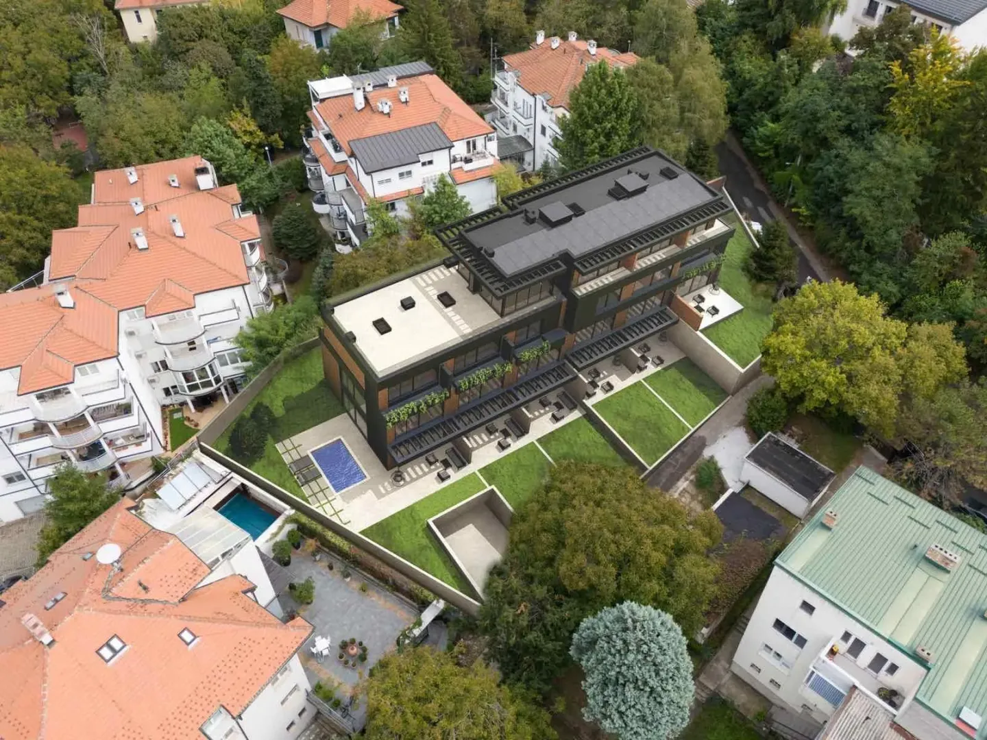 Pogled iz vazduha na modernu stambenu zgradu sa uređenim dvorištem i bazenom.