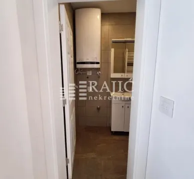 Pogled na manje kupatilo sa belim elementima i bojlerom na zidu. - image 9