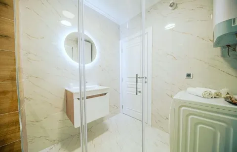 Modern bathroom with a vanity, backlit mirror, and washing machine. - image 7