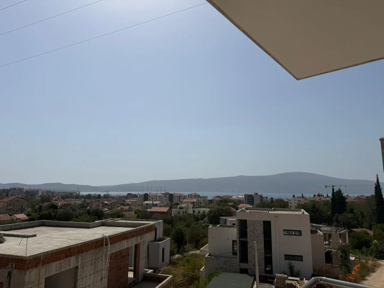 Pogled sa terase na gradsko naselje i brda u daljini.