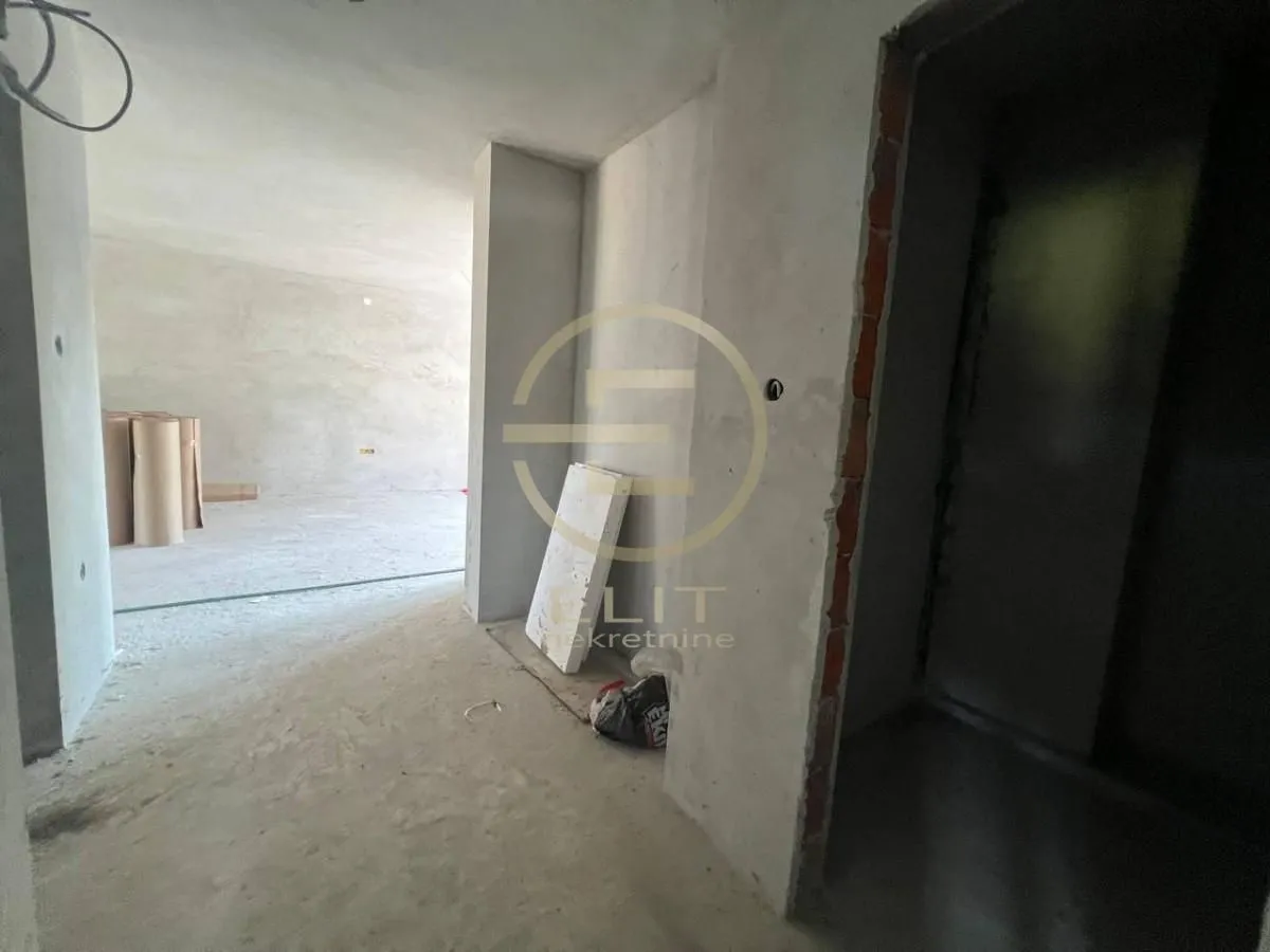 Neuređen prostor u grubim radovima sa zidovima od maltera i betonskim podom.