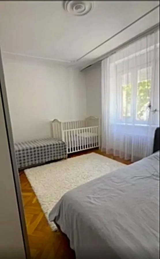 Spavaća soba sa krevetom, krevetcem za bebe i parketom na podu.