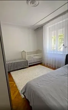 Spavaća soba sa krevetom, krevetcem za bebe i parketom na podu. - image 8