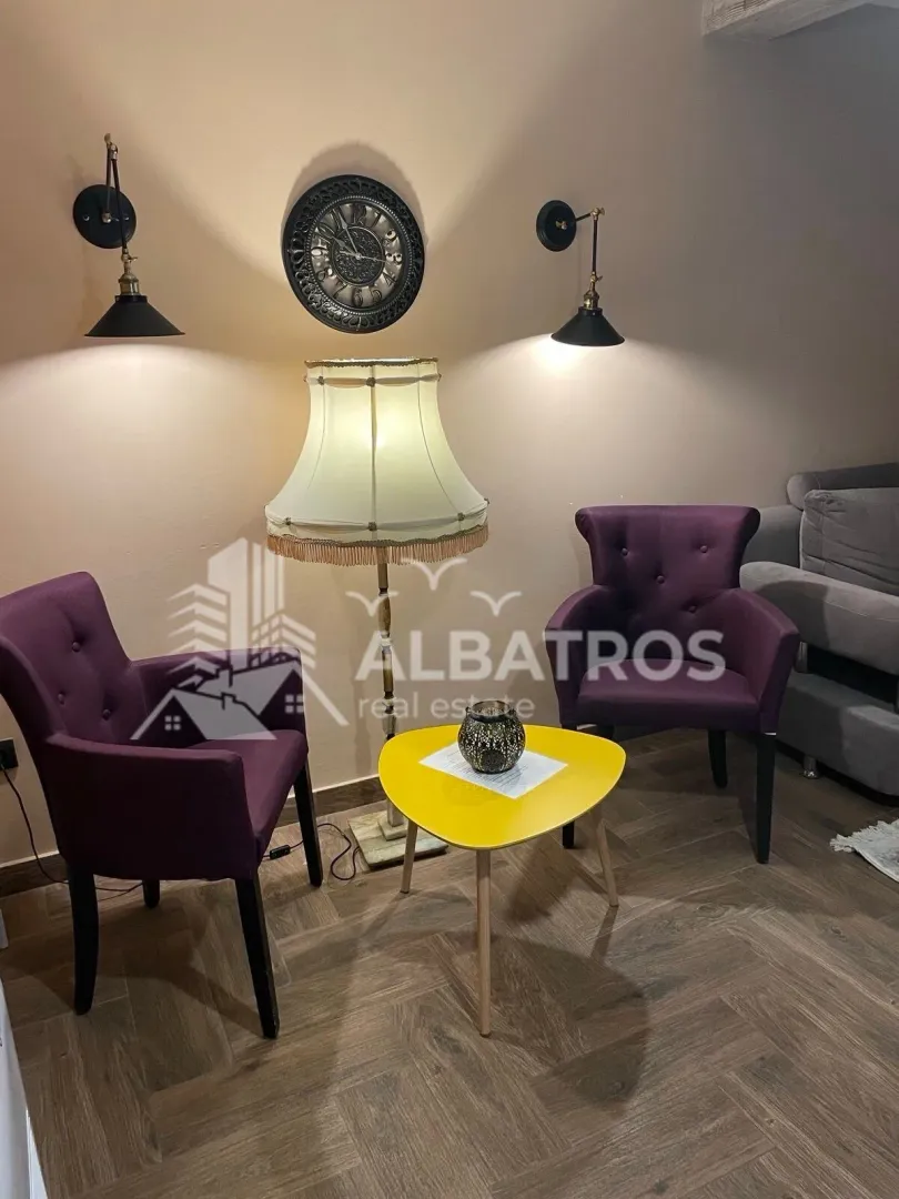Living room with two purple armchairs, a coffee table, and a lamp.