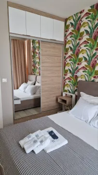 Modern bedroom with a double bed, wardrobe, and botanical wallpaper. - image 13